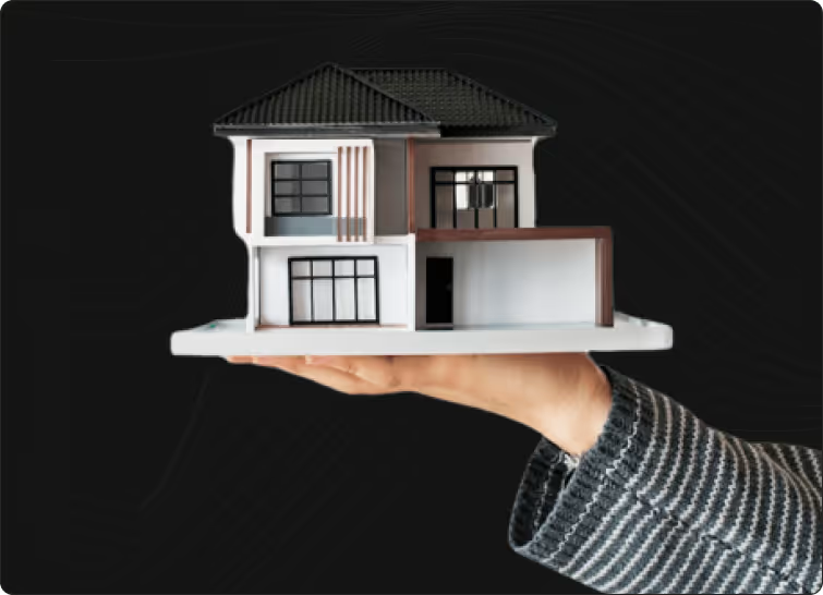 A scale model of a modern house held in an open hand